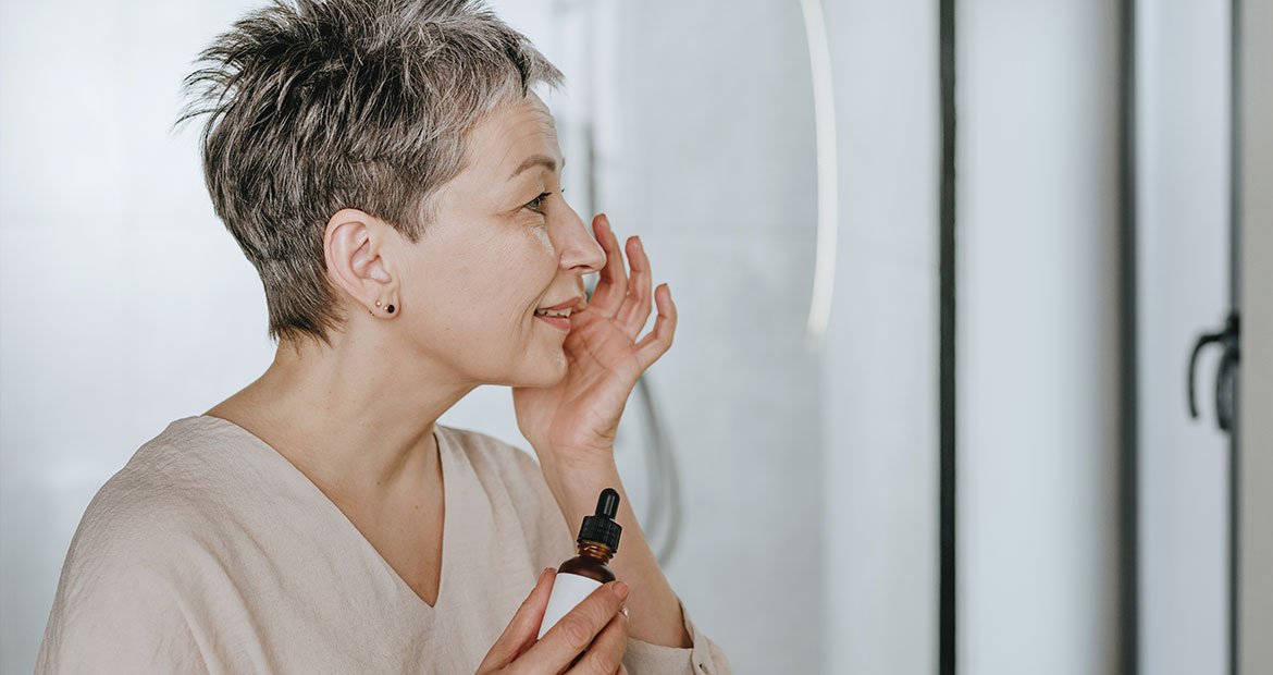 mulher branca de cabelo curtos aplicando produto para estimular colágeno na pele